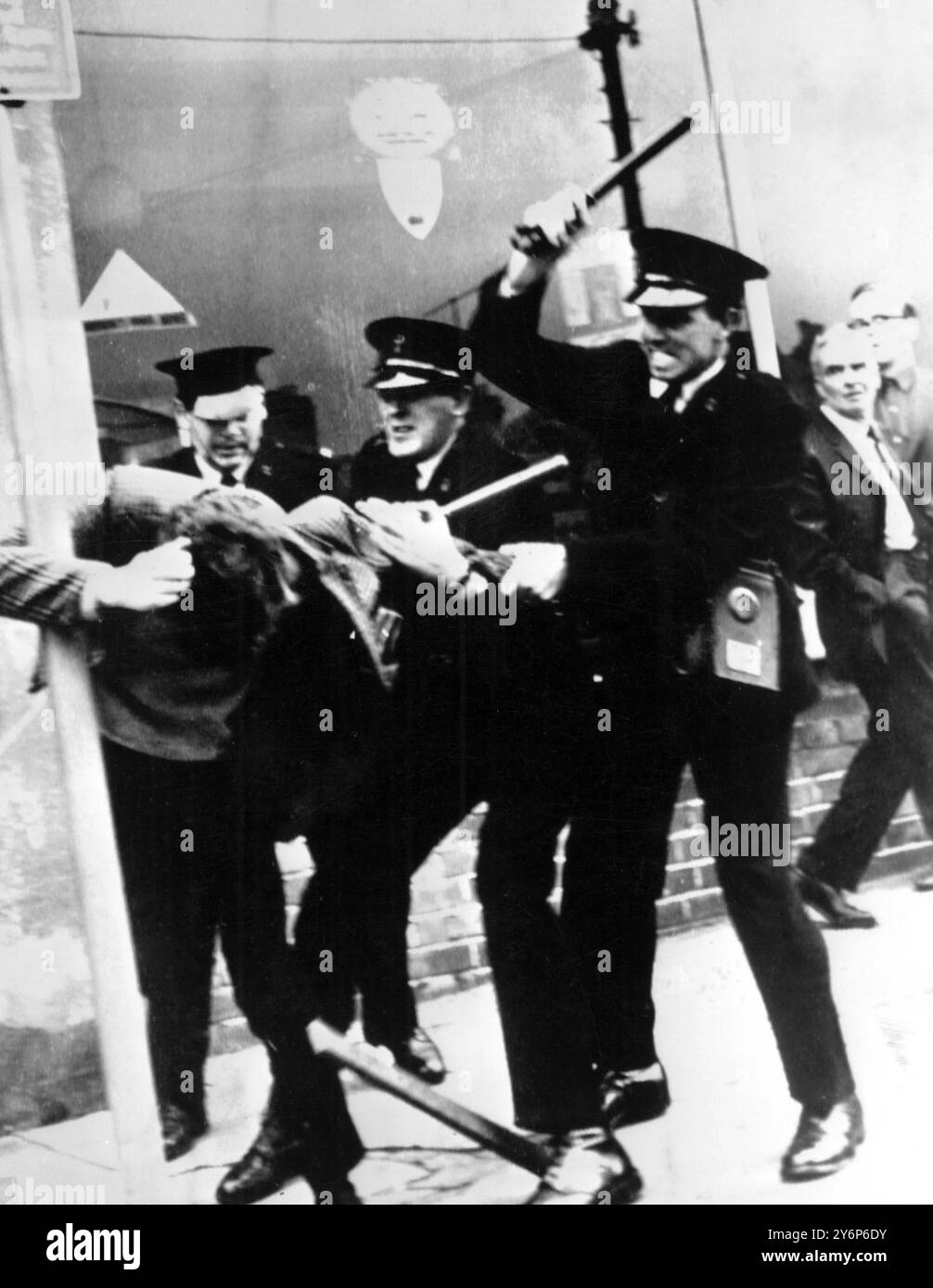 Tre poliziotti che maneggiano bastoni si avvicinano ai manifestanti a Londonderry il 6 ottobre 1968 durante violenti scontri tra manifestanti e polizia. La rivolta iniziò sabato quando i manifestanti chiesero cambiamenti nel sistema elettorale e protestarono contro la discriminazione religiosa. Ulteriori manifestazioni sono scoppiate domenica per protestare contro la presunta brutalità della polizia nei disturbi del sabato. 7 ottobre 1968 Foto Stock