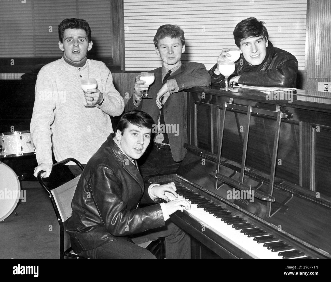 Niente come un bicchiere di latte dopo una giornata estenuante - o almeno sembra essere l'opinione dei Searchers, nella foto di Londra . Da sinistra a destra sono Tony Jackson, Mike Pender (seduto), John McNally e Chris Curtis. Avevano appena registrato alla ATV House. 26 febbraio 1964 Foto Stock
