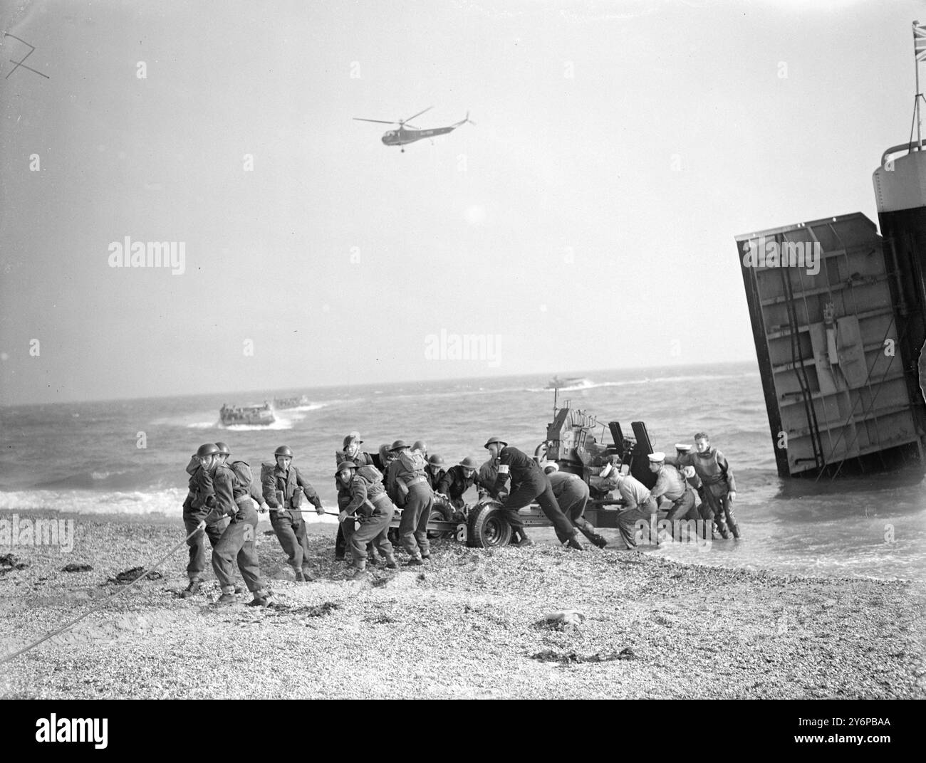 SI TRATTA Di Un'OPERAZIONE COMBINATA la più grande dimostrazione di operazioni combinate da quando la guerra era di stanza a Portsmouth per il beneficio degli ufficiali dell'Army staff College, Camberley, Surrey ' frogmen' e mezzi d'assalto con lanciafiamme assaliti a terra mentre le mine esplodevano sulla spiaggia e i getti zoomavano dalla portaerei Theseus' . Guardando l'esercitazione Camberley erano ufficiali dell'esercito provenienti dal Marocco e da diversi altri paesi. IMMAGINI :- White - Capped Sailors aiuta gli artiglieri a trascinare un cannone antiaereo bofors a terra da un carro armato - atterraggio durante l'esercitazione. un elicottero vola ov Foto Stock