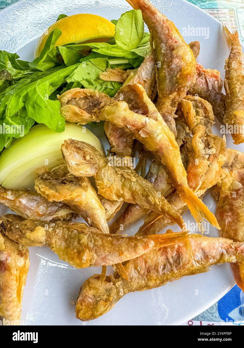 piccolo pesce fritto in piatto bianco con cipolla e limone . Foto di alta qualità Foto Stock