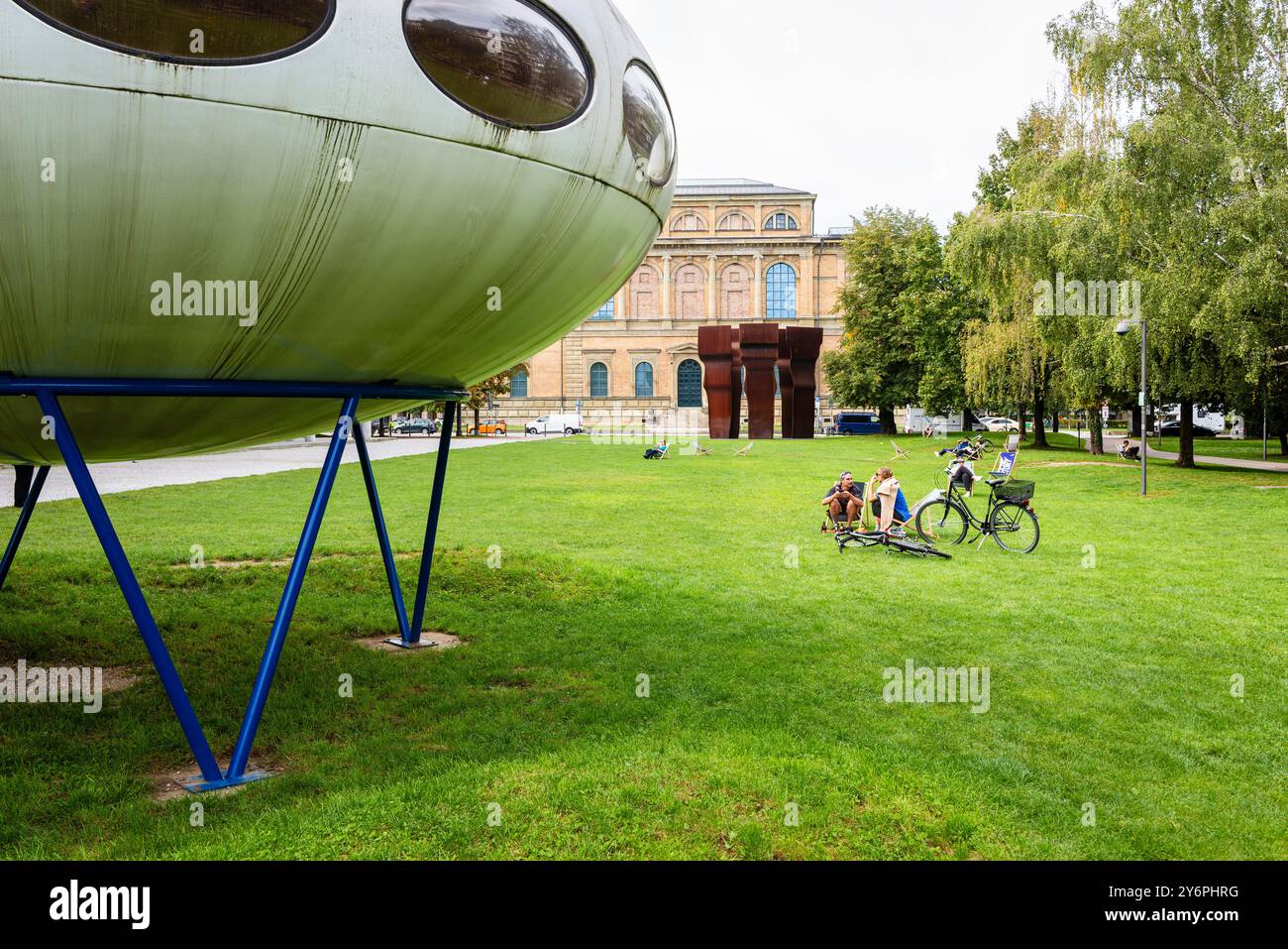 Persone sedute su sdraio sul prato di fronte alla Pinakothek der moderne e all'installazione artistica futuro House di Matti Suuronen, Monaco di Baviera Foto Stock
