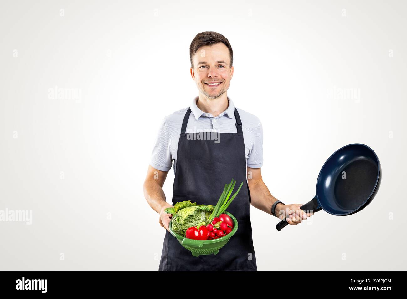 Uomo in grembiule con verdure fresche e teglia da cucina Foto Stock