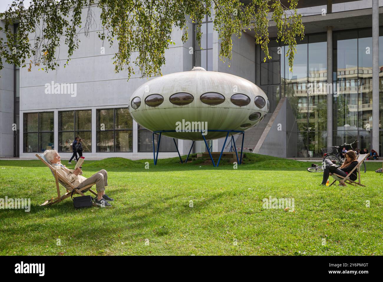 Persone sedute su sdraio sul prato di fronte alla Pinakothek der moderne e all'installazione artistica futuro House di Matti Suuronen, Monaco di Baviera Foto Stock
