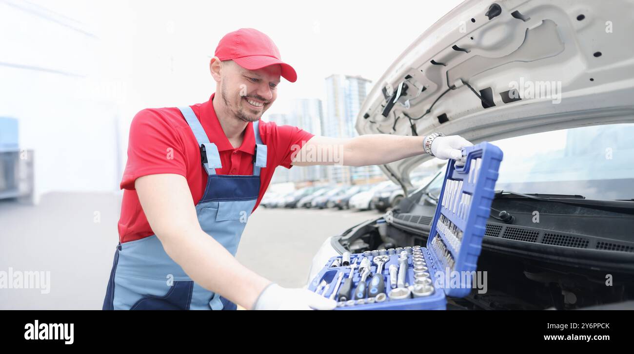 Tecnico automobilistico sorridente e kit aperto pieno di attrezzature Foto Stock