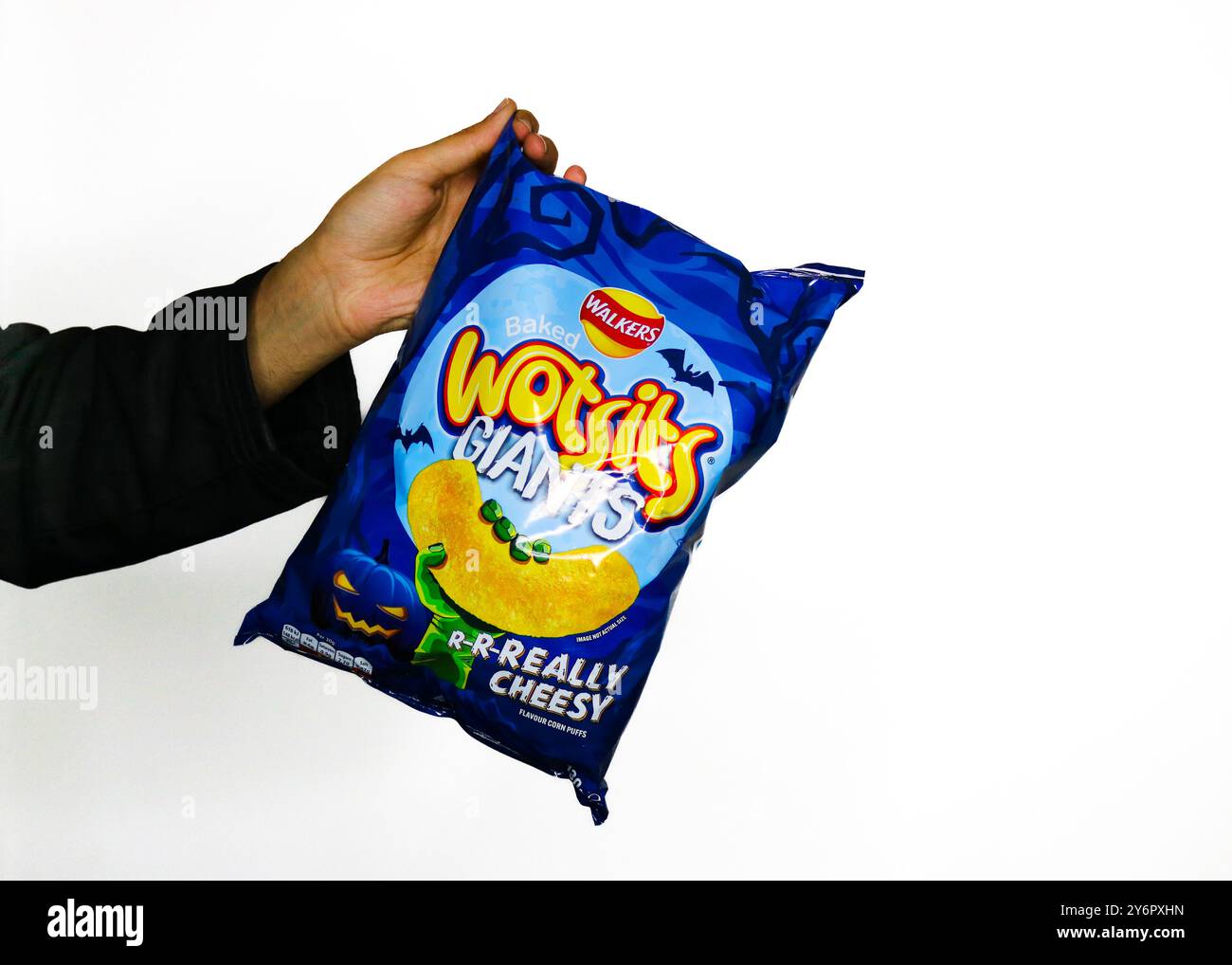 Londra, Inghilterra, settembre 26 2024: Braccio che afferra una borsa di Halloween Walkers Wotsit con uno sfondo bianco con marchio per Halloween 2024 Foto Stock