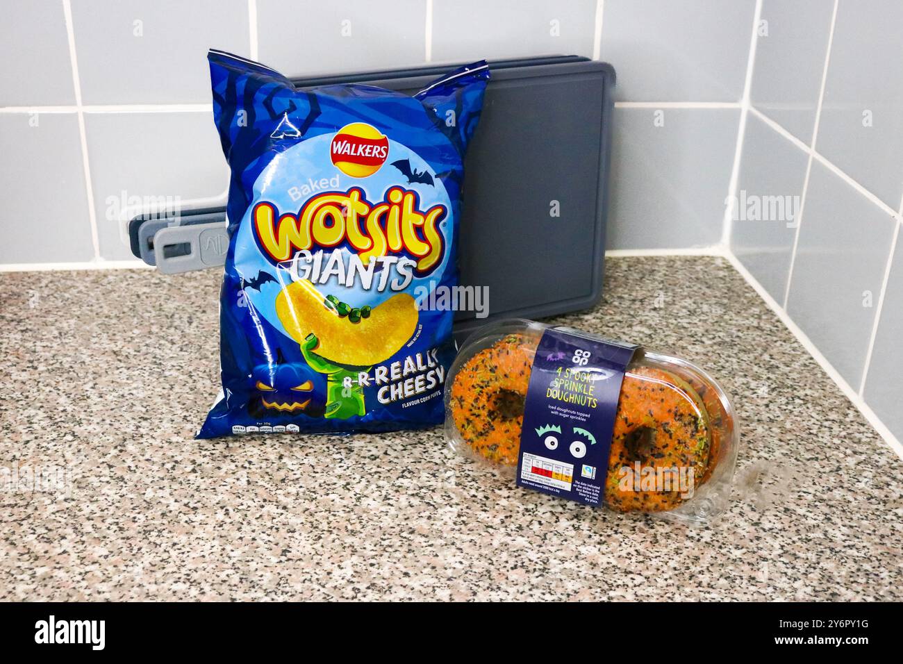 Londra, Inghilterra, settembre 26 2024: Cibo marchiato Halloween, sacchetto di patatine e ciambelle in cucina a casa Foto Stock