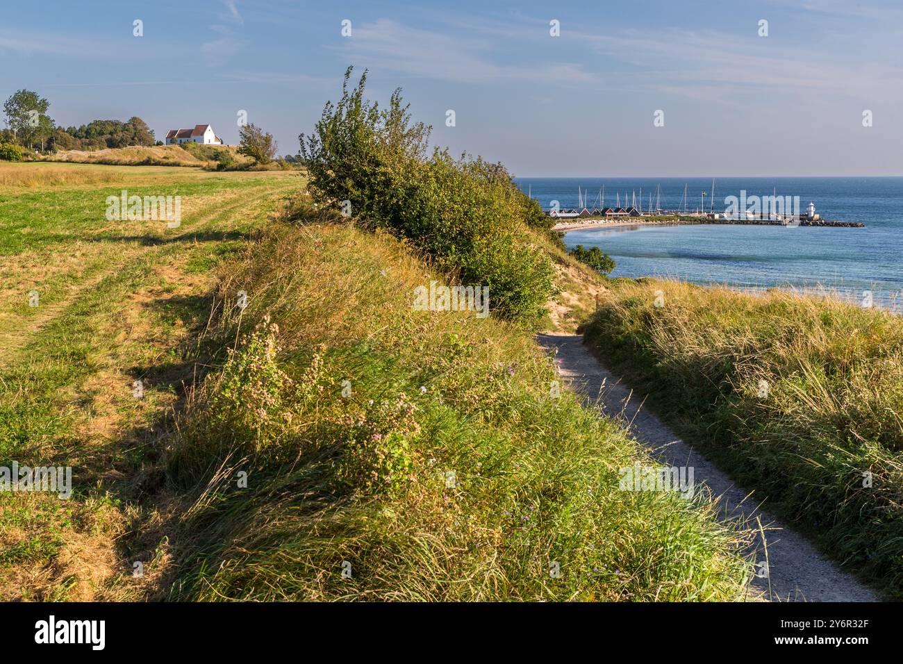 Chiesa di Sankt Ibbs sull'isola di Ven con porto e una sezione del percorso ciclistico ed escursionistico che conduce intorno alla piccola isola nel Öresund. Kyrkvägen, Landskrona kommun, Skåne, Svezia Foto Stock