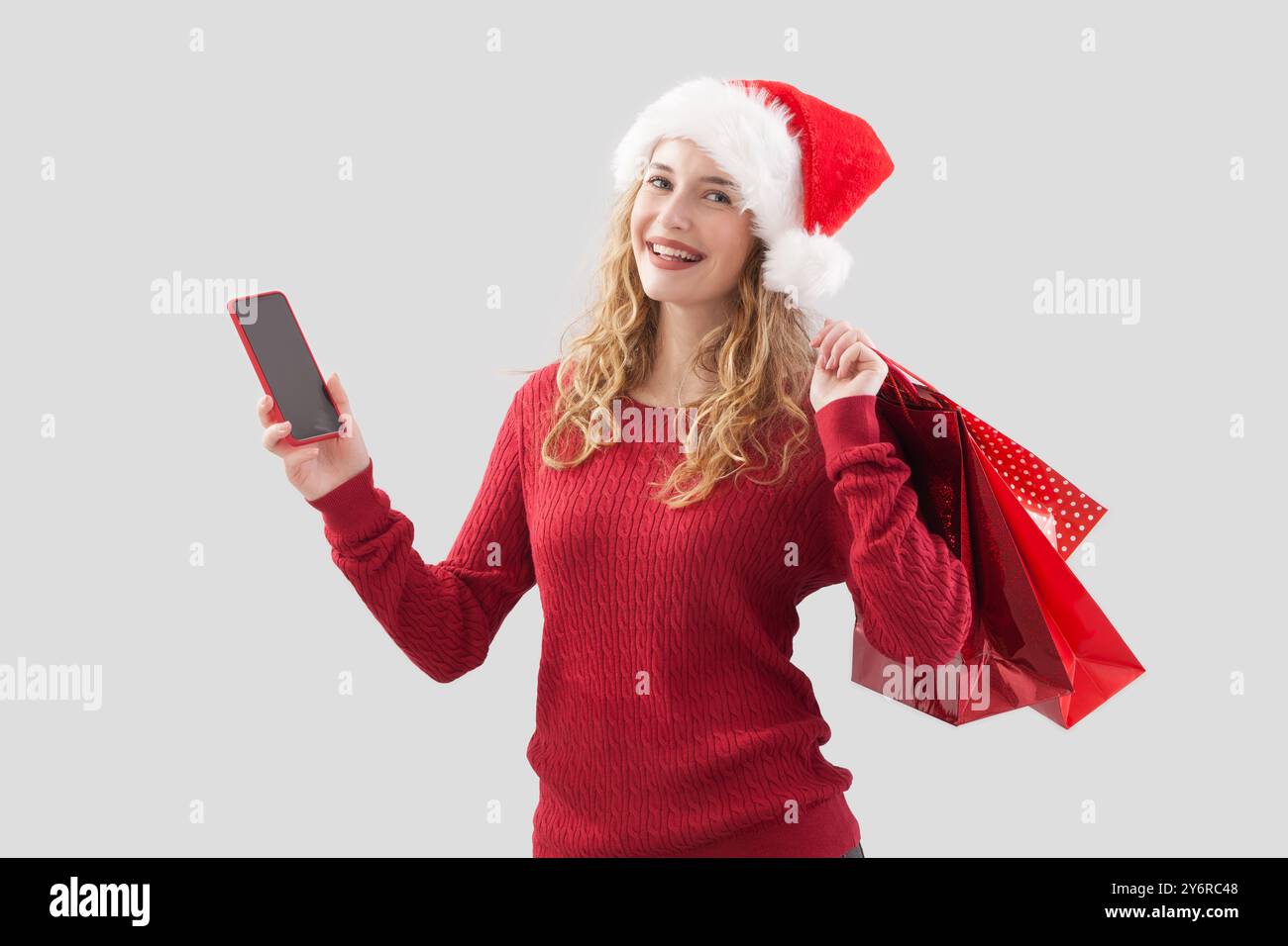 Felice Babbo Natale donna con cellulare e buon regalo di Natale borse per gli acquirenti rosse. Promozione vendita offerta, shopping online, banner pubblicitari, p Foto Stock