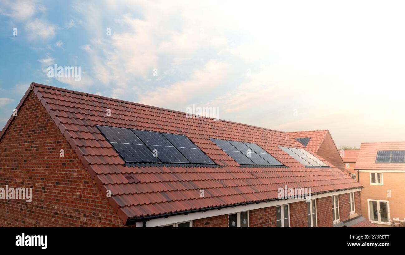 Il tetto di una fila di case di nuova costruzione in un cantiere con tetto integrato o pannelli solari a tetto per un'energia economica e sostenibile in un ambiente ecologico Foto Stock