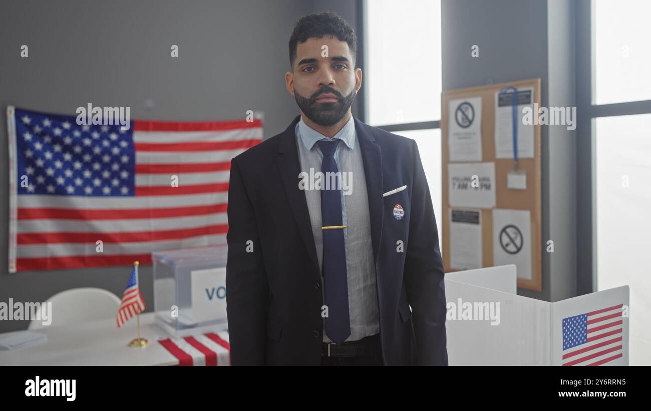 Un ispanico con una tuta si trova con fiducia in una postazione di voto con bandiere americane, che rappresenta il processo democratico. Foto Stock