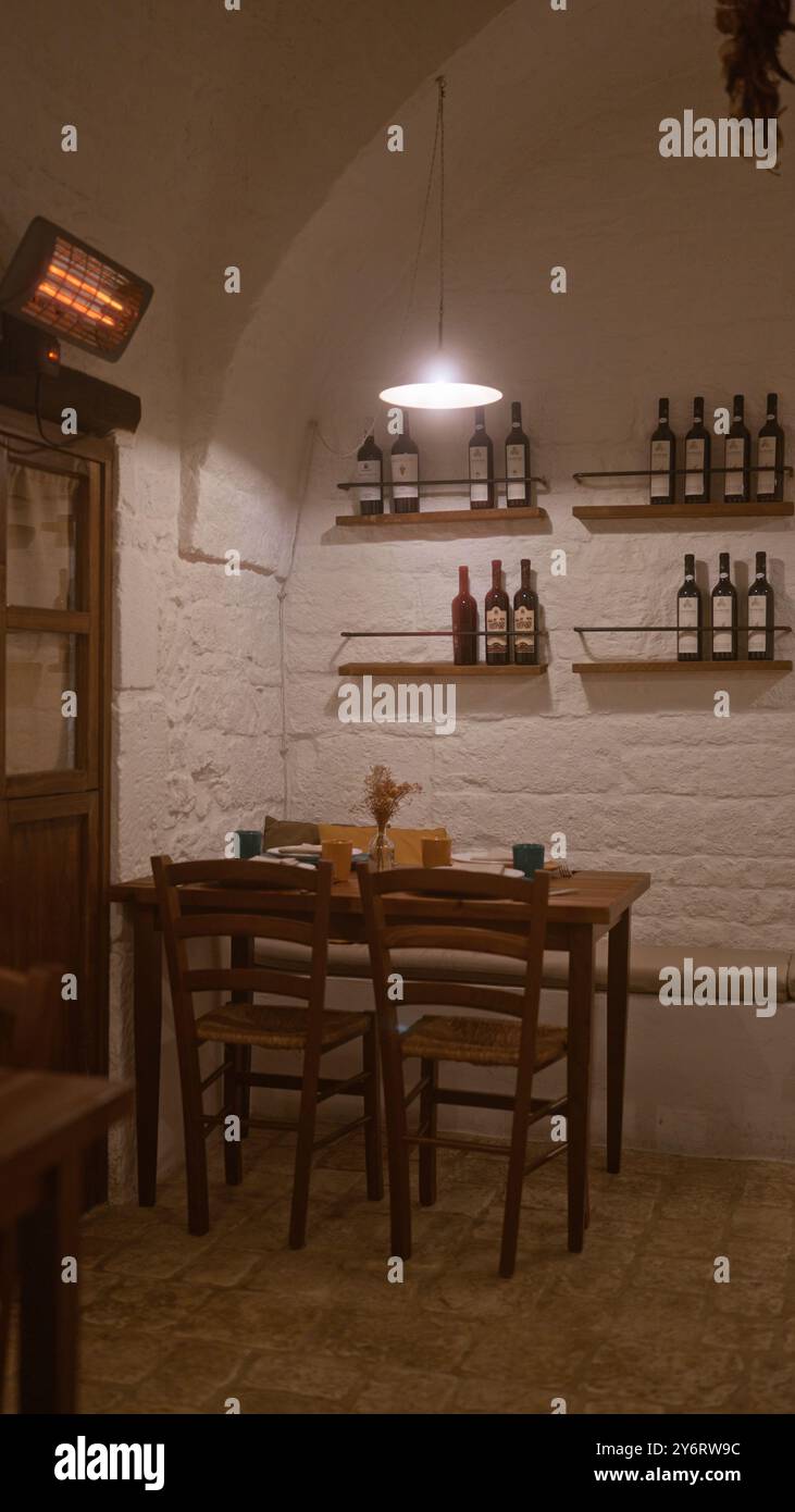 Un intimo ristorante italiano all'interno con un'accogliente disposizione dei tavoli, pareti in mattoni rustici, sedie in legno, scaffali di bottiglie di vino e illuminazione soffusa Foto Stock