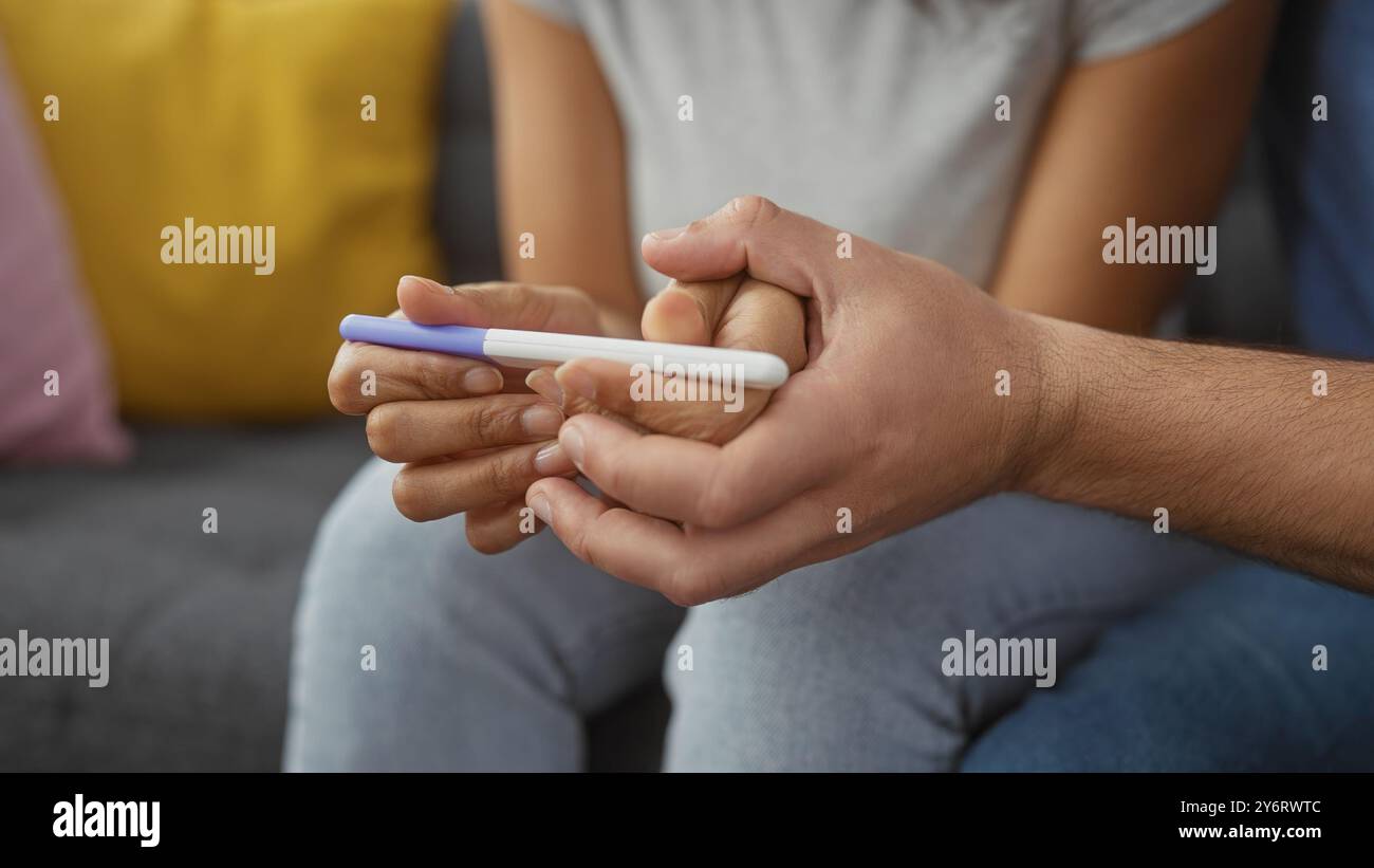 Un uomo e una donna in ansia in attesa dei risultati di un test di gravidanza in un salotto accogliente. Foto Stock