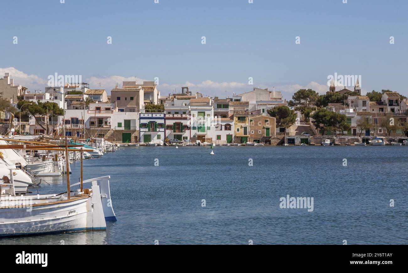 Tranquillo porto con barche in primo piano e colorati edifici lungo la costa sotto un cielo blu, Portocolom, Maiorca, Isole Baleari, Spagna, EUR Foto Stock