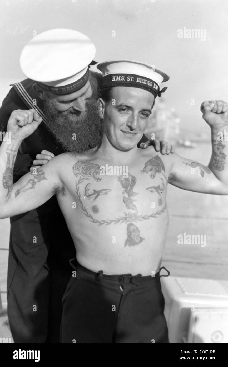 IL MARINAIO CON LA BARBA PIÙ LUNGA Portsmouth, Hants, il marinaio con la barba più lunga a bordo di H.M.S. St. BRIDE'S BAY , È L/SEA. "POLLY" PARROTT DI LONDONDERRY, CHE RIESCE A VEDERE DIVERSE CARATTERISTICHE DEL MONDO TATUATE SUL PETTO DEL SUO COMPAGNO. L'UOMO PIÙ TATUATO DELLA NAVE È A/B FRANK VENNELL DI CLACT0N-on-Sea, Essex e visto sul petto, sono tigri, pesci, Una "PISTOLA-IMBALLAGGIO MOMA", Una GEISHA GIRL, UN PAVONE E UN VICHINGO, UN EAGLE TATUATO PORTA UN UNION JACK E UNA GHIRLANDA DI VERDE SI ESTENDE ATTRAVERSO IL PETTO DEI MARINAI. 29 GENNAIO 1962 Foto Stock