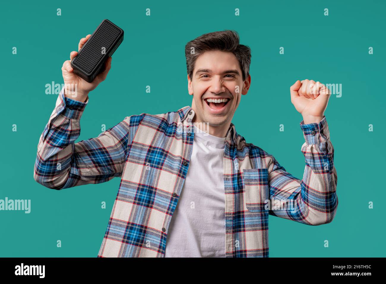 Giovane e bello che ascolta la musica con l'altoparlante portatile wireless - sistema audio Foto Stock