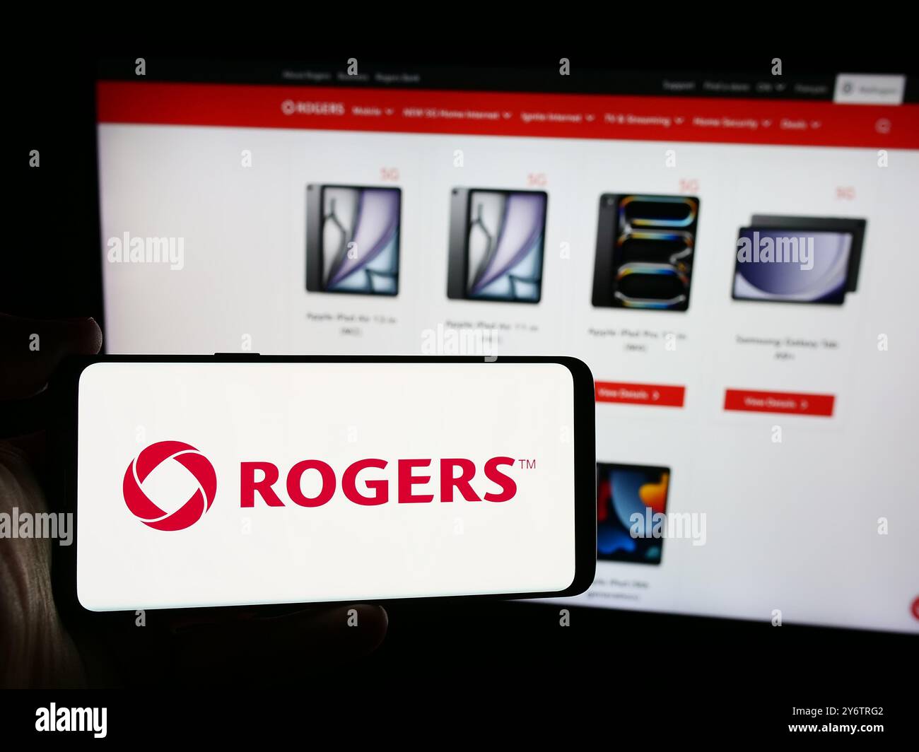 In questa immagine, una persona ha in mano uno smartphone con il logo della società canadese di comunicazioni Rogers Communications Inc. Davanti al sito Web. Foto Stock