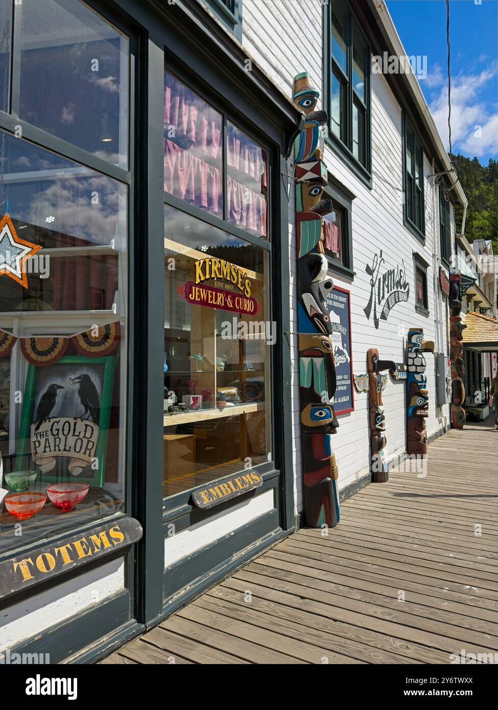 Vetrine, pali totemici e un marciapiede in legno contribuiscono all'attrattiva turistica di una strada laterale a Skagway, Alaska. Foto Stock