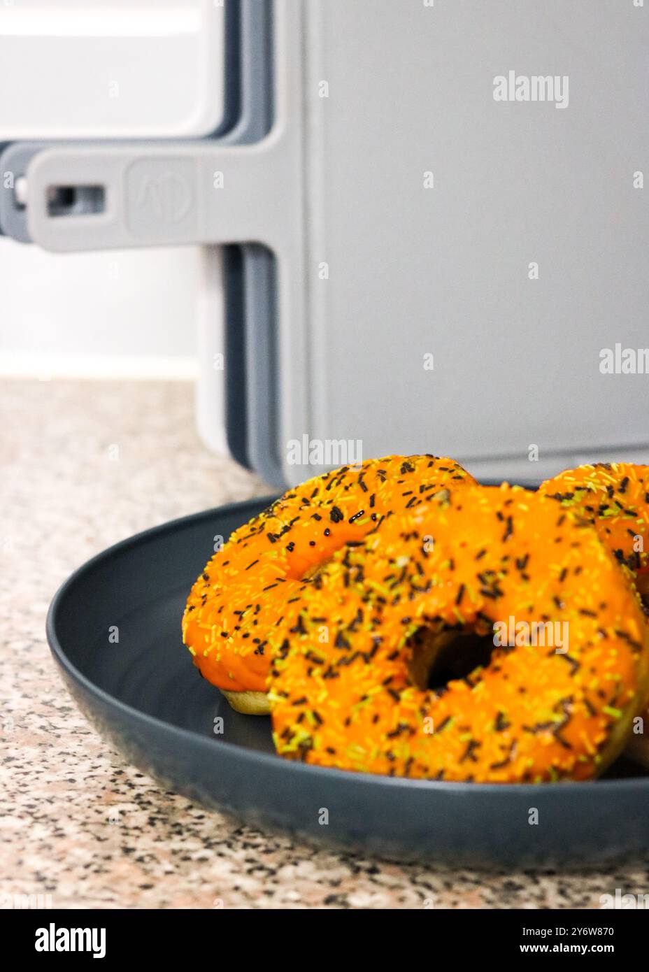 Ciambelle a tema Halloween con glassa arancione, spruzzi di bianco e nero per le festività natalizie Foto Stock