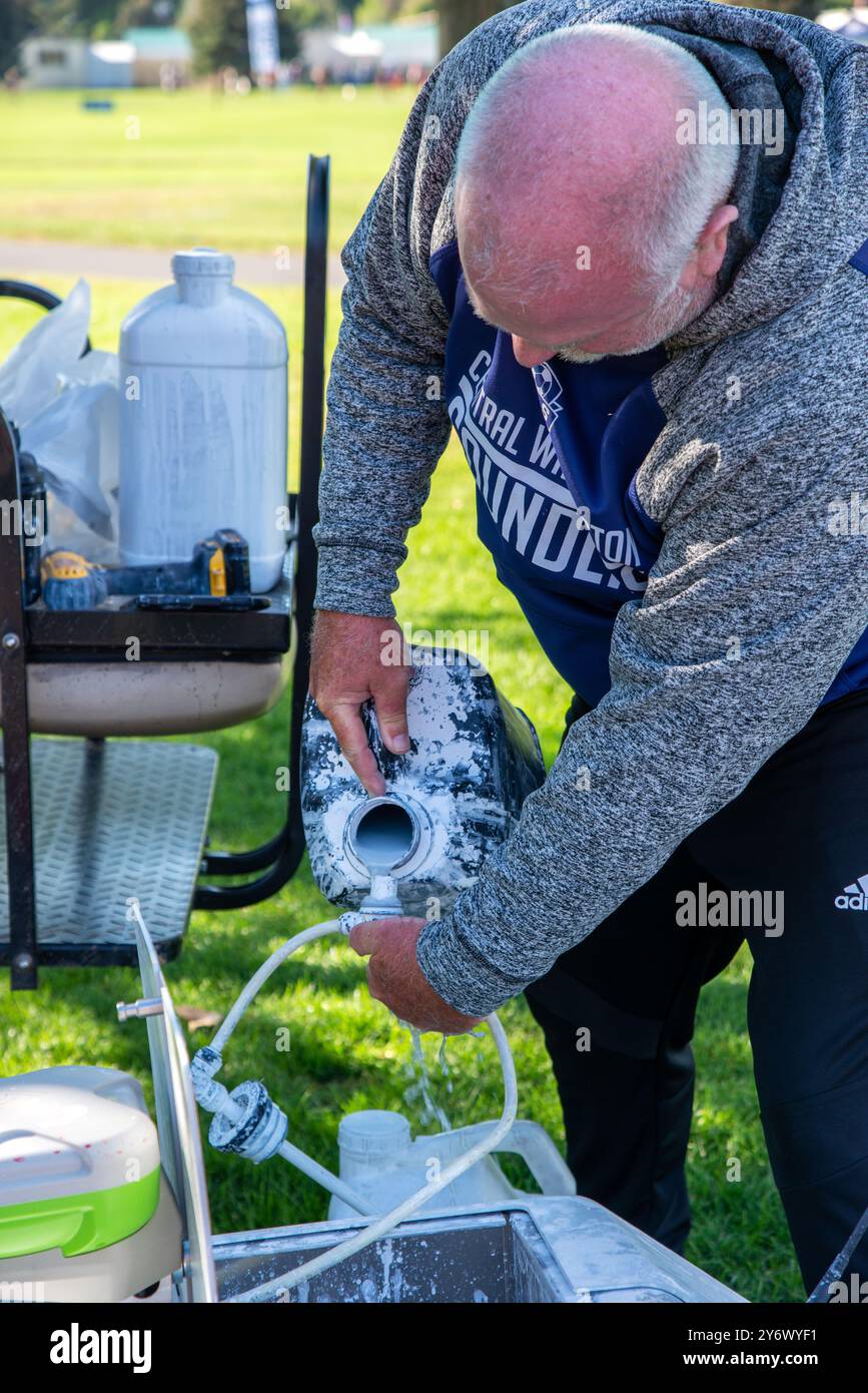 Un maschio adulto programma un robot mobile remoto per dipingere le linee su un campo di calcio a Yakima, Washington. STATI UNITI Foto Stock