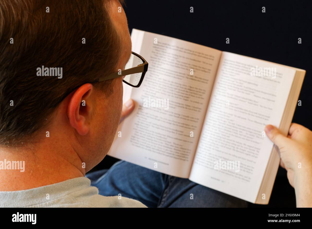 Immagine a spalla di un uomo che legge un libro Foto Stock
