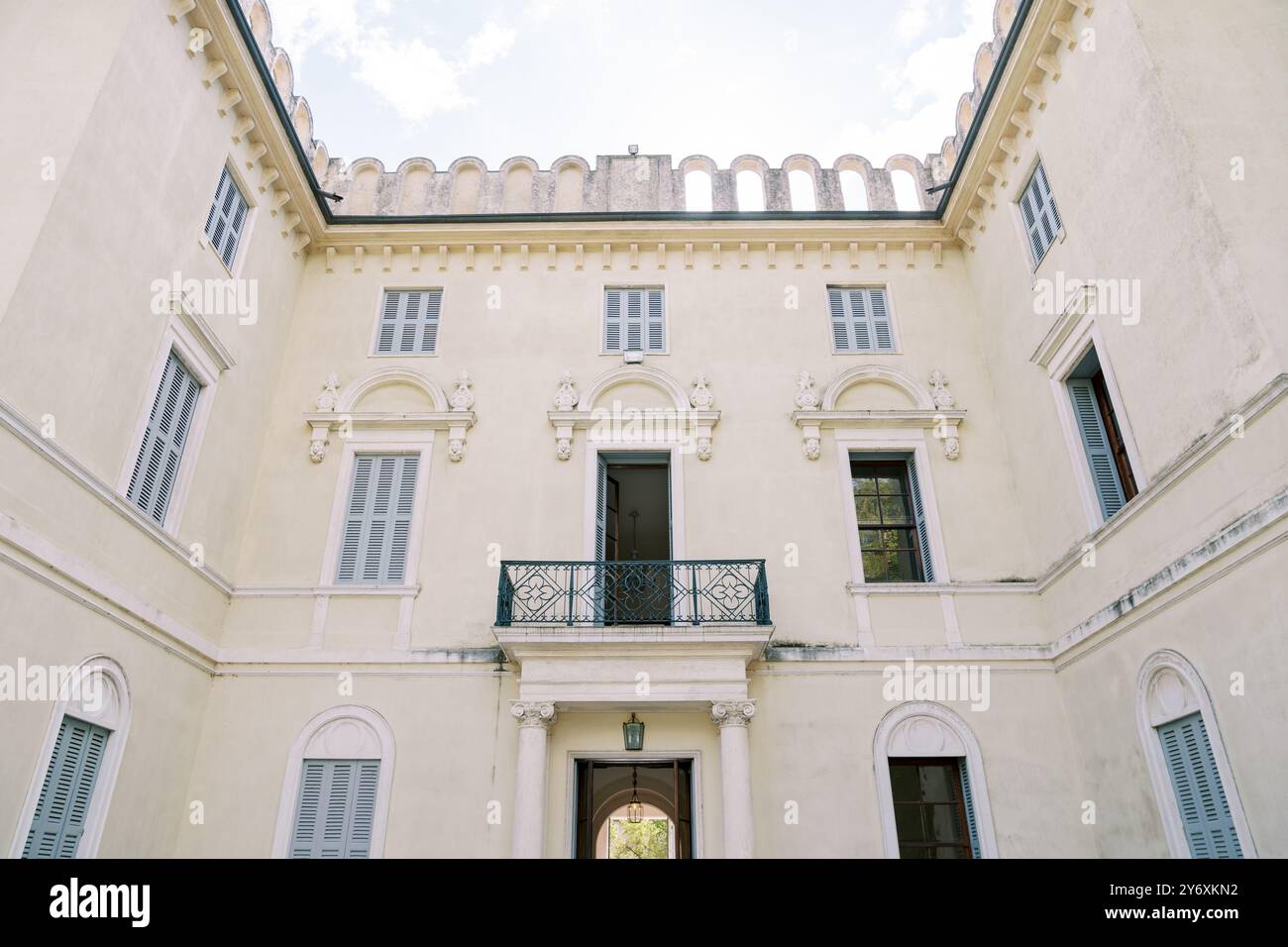 Facciata interna ad angolo di un'antica villa con balcone in ferro battuto e stucco Foto Stock