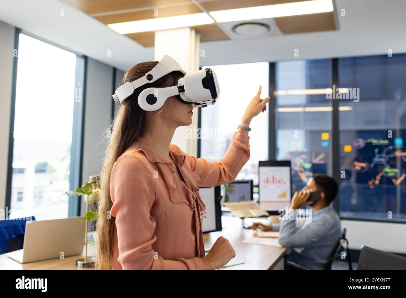 Utilizzando il visore VR, donna che interagisce con l'ambiente virtuale in un ufficio moderno Foto Stock