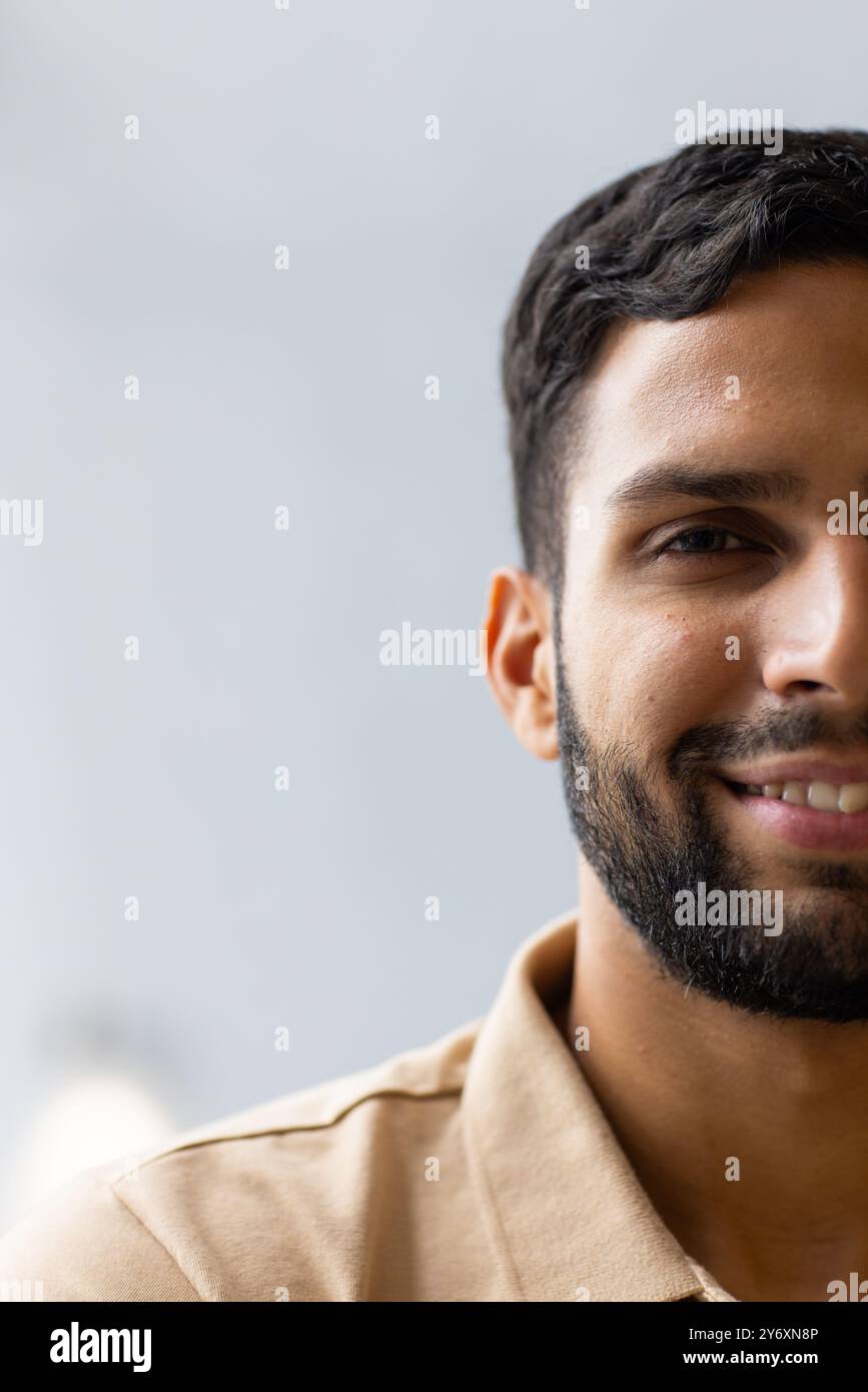 Uomo sorridente con barba che indossa una camicia beige, guarda la fotocamera, primi piani, copia spazio Foto Stock