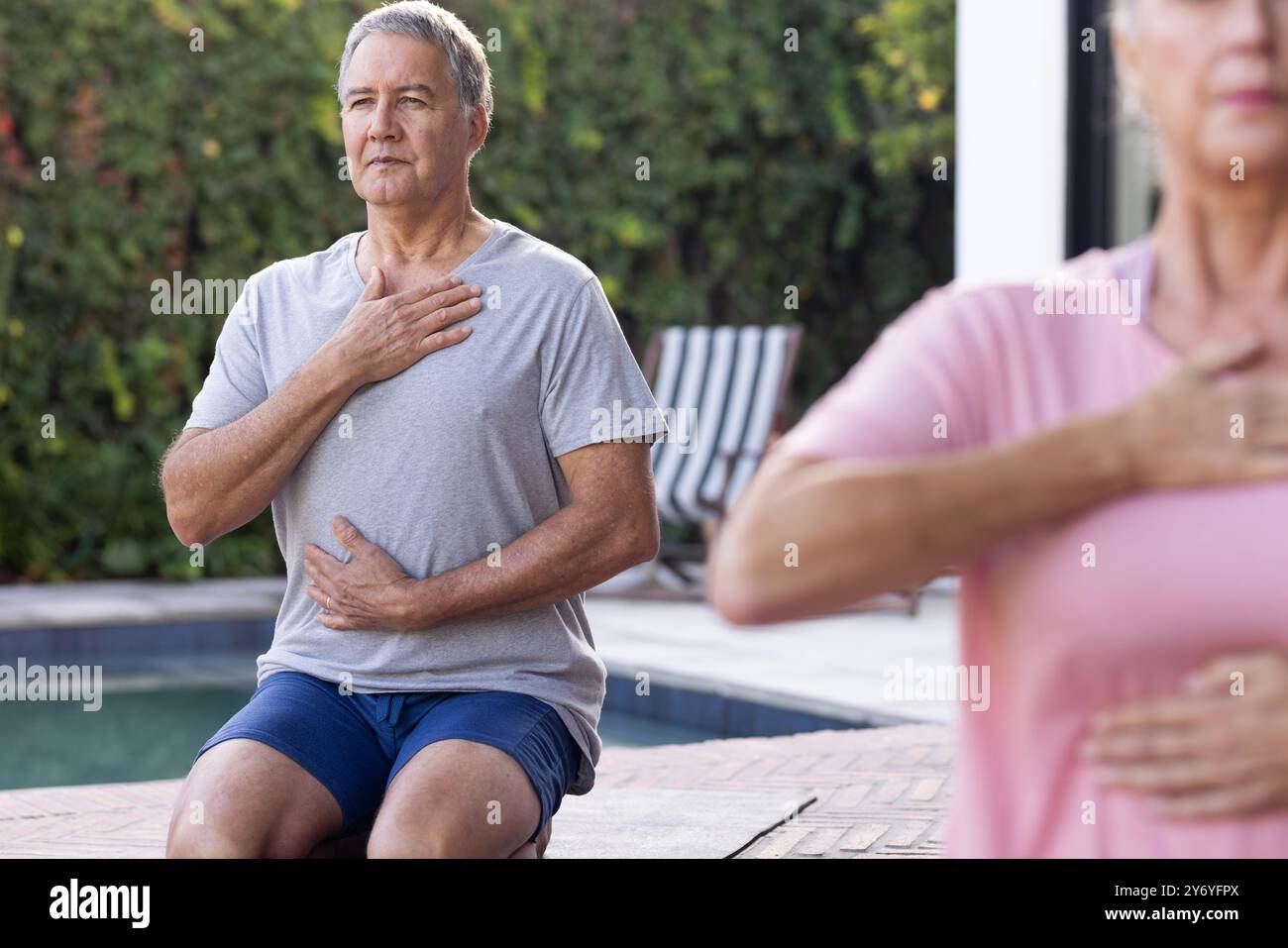 Pratica yoga, uomo anziano e donna che meditano all'aperto in piscina, a casa. meditazione, benessere, fitness, relax, consapevolezza, stile di vita sano Foto Stock