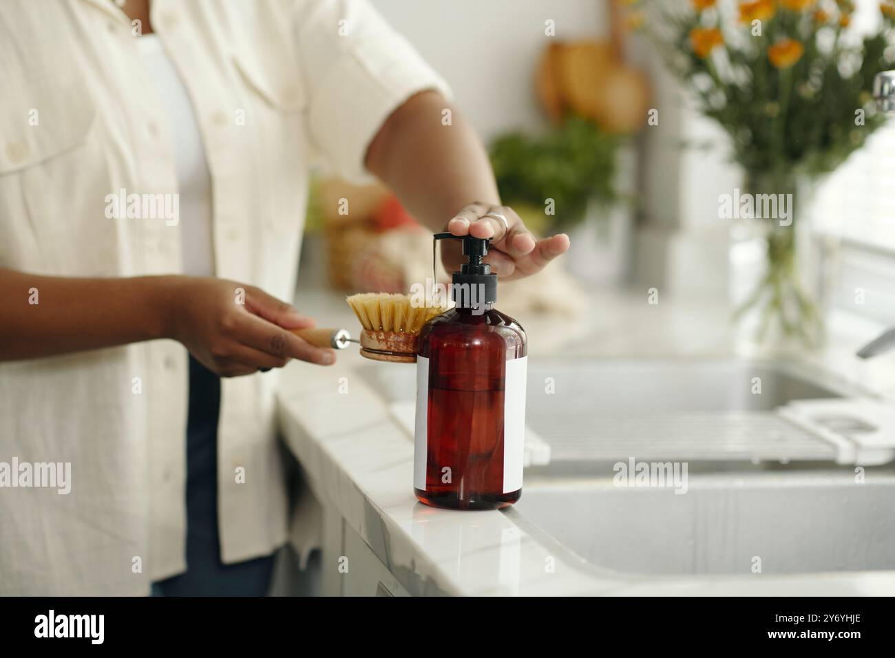 Persona che utilizza un dispenser di sapone in cucina vicino al lavandino Foto Stock