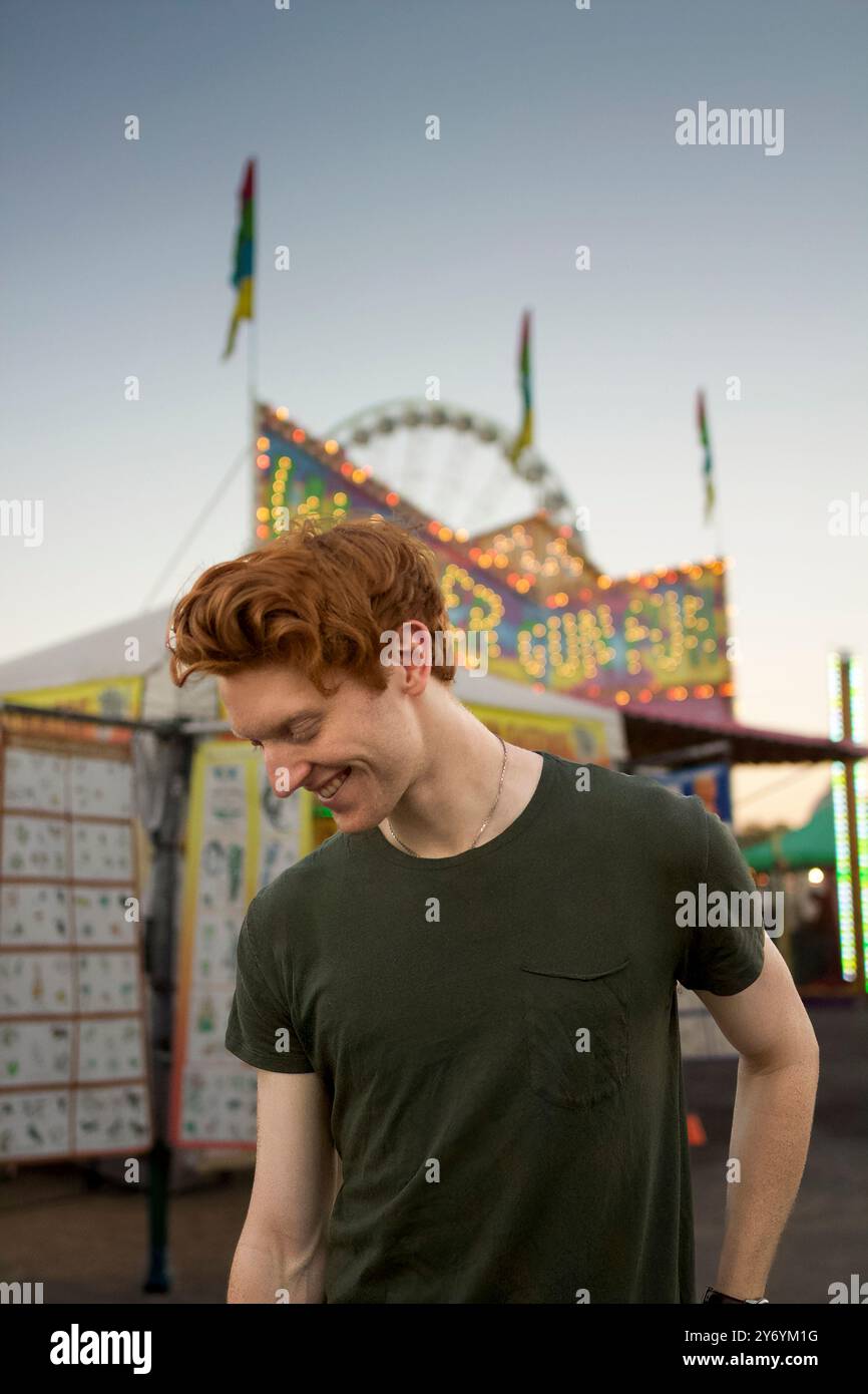 Un giovane sorride davanti a un colorato carnevale Foto Stock