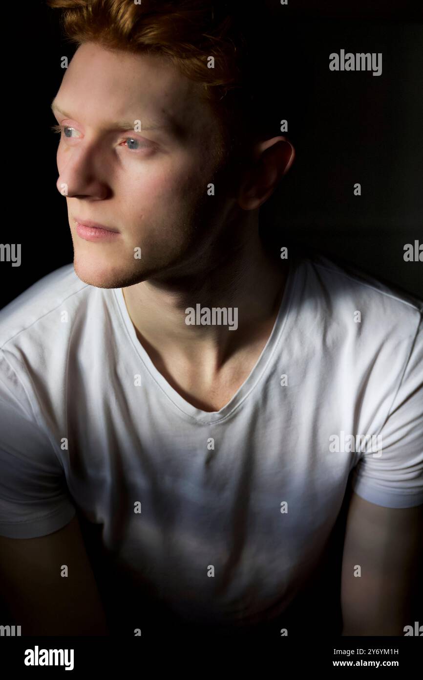 Un giovane attento con i capelli rossi guarda in lontananza Foto Stock