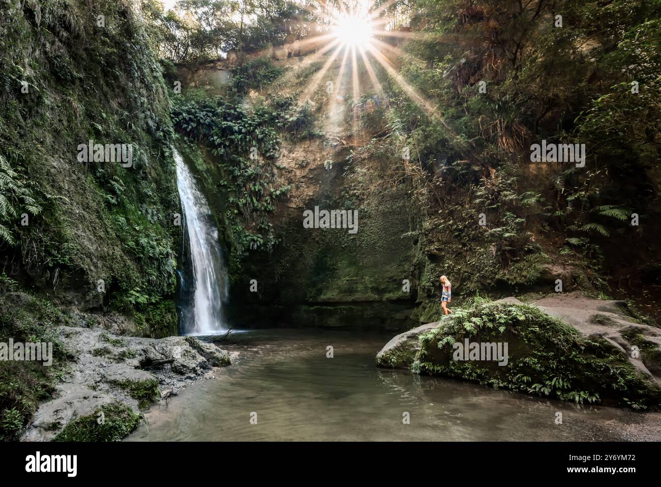 Ragazza che cammina nella splendida valle verde soleggiata con cascata Foto Stock