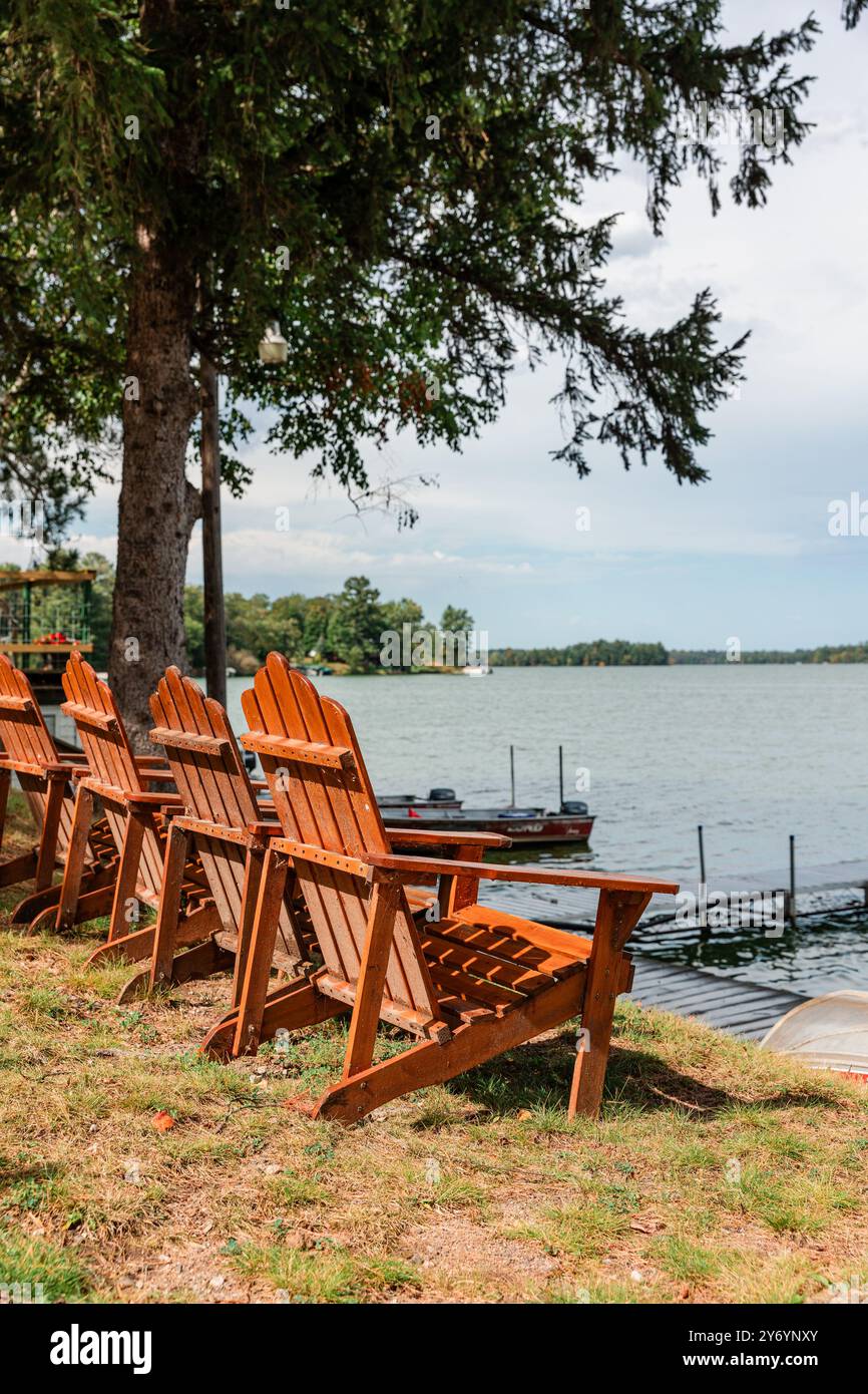 Sedie Adirondack che si affacciano sul lago lungo la costa Foto Stock