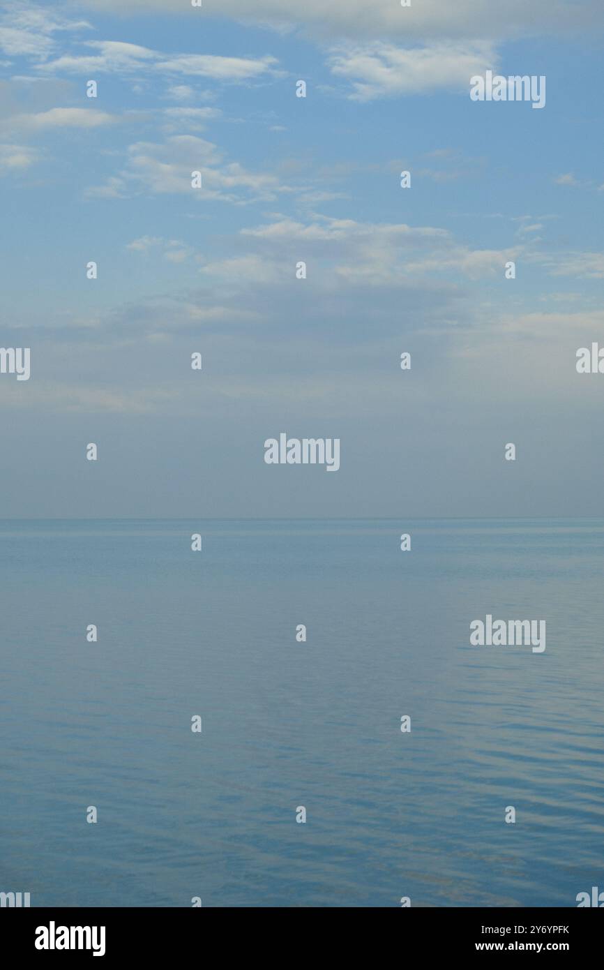 scena tranquilla dove l'acqua incontra il cielo e l'orizzonte si fonde Foto Stock