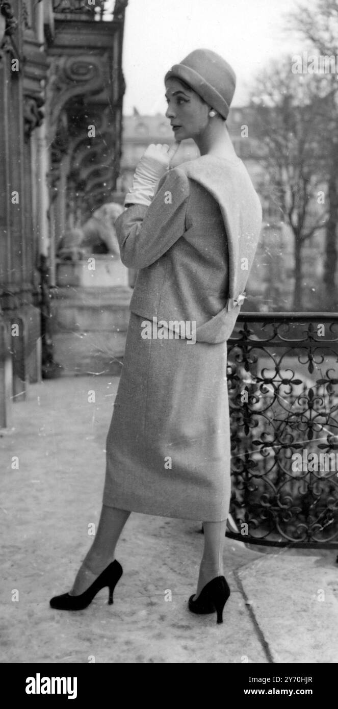 In questa estate abito a due pezzi della collezione Primavera ed Estate 1956 del De Givenchy di Parigi , l' interesse è focalizzato sul retro della giacca , che ha un pannello a forma di X detatchabile legato in vita con uno stretto arco in gros grain . La tuta è di colore blu e grigio e si fissa sul davanti con quattro bottoni sotto uno scollo senza colletto . Il cappello è in paglia viola. 20 marzo 1956 Foto Stock