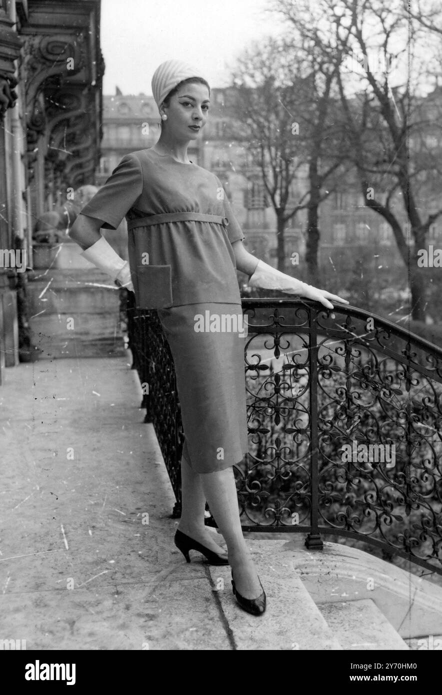 La linea di vita rialzata è accentuata in questa estate in due pezzi di serge di seta arancione creato da De Givenchy . Per contrasto, un vaso di fiori in malva a righe e taffetas bianche. 20 marzo 1956 Foto Stock