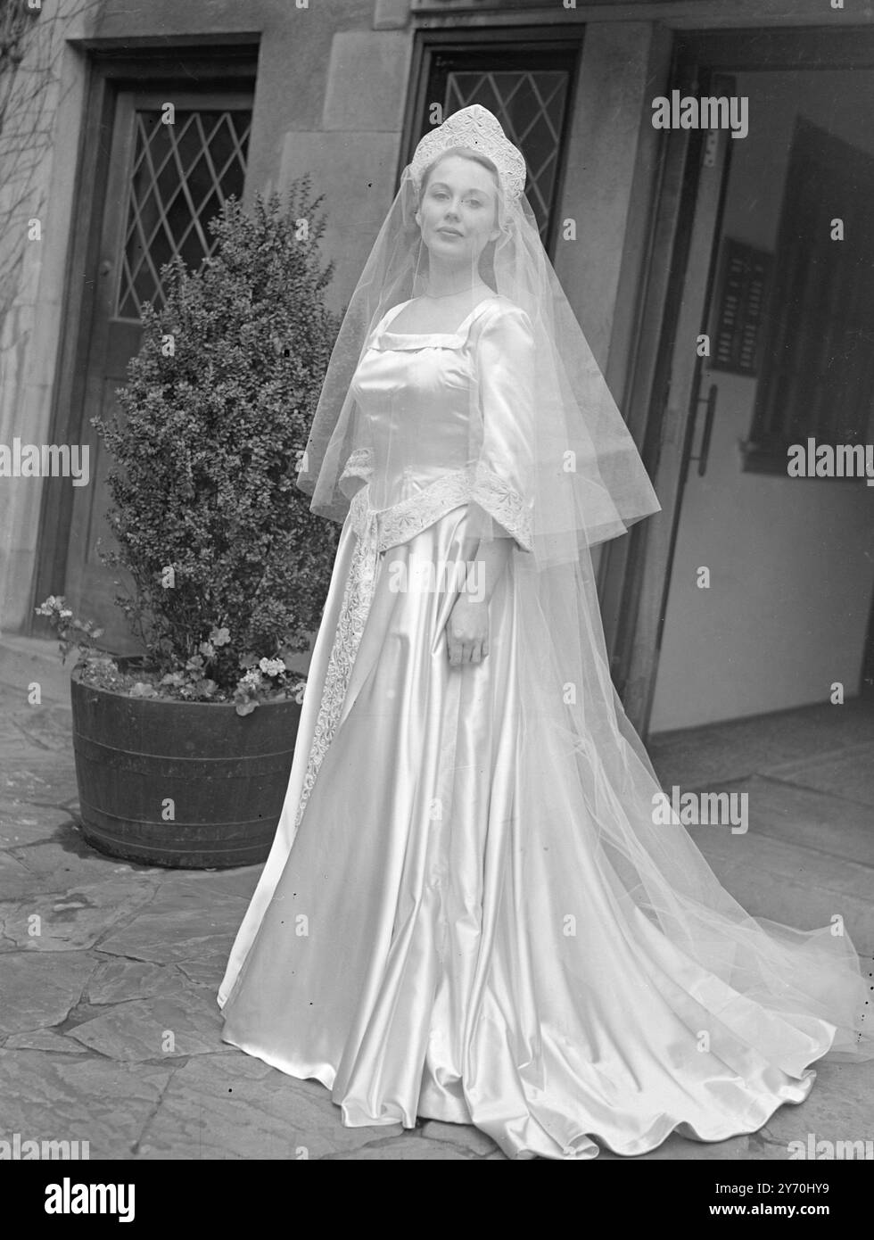 IL LUNGOMETRAGGIO COMPLETO in puro raso bianco, l'attrice cinematografica Hazel Court, ventitreenne, è visto oggi mentre stava per lasciare Grantham Court, Brick Street, W., per il suo matrimonio con l'attore Dermot Walsh nella chiesa di St. James, Spanish Place, Londra. L'abito è molto pieno, con una fascia medievale, e incorpora polsini rivolti ricamati con bianco e rosso incrostati con oro. 2 luglio 1949 Foto Stock