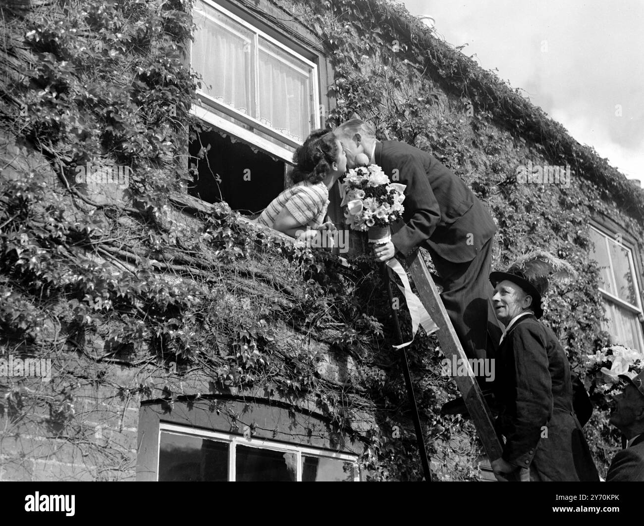 TUTTI-MAN, IN SCALA, SOSTIENE IL SUO BACIO il diritto di baciare le ragazze più belle della città fu rivendicato dai tutti (o titipizzazione) uomini di Hungerford, Berkshire, quando vi ebbe inizio l'annuale festa dell'Hocktide. Dopo che la corte di Hocktide aveva eletto tutti, gli uomini venivano date le tradizionali bacchette d'ufficio, le stalle decorate con fiori. Essi esercitarono quindi il privilegio di raccogliere un centesimo da ogni residente o di baciare la ragazza più bella sul posto. Le celebrazioni commemorano la concessione di diritti di pesca libera e di terra comune da parte di Giovanni di Gaunt 600 anni fa . Foto Stock