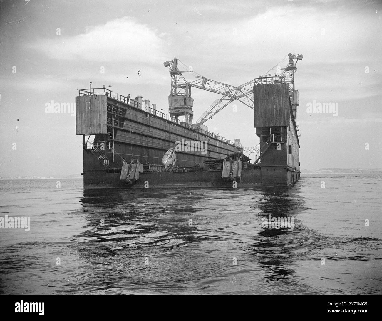675.000 sterline AL MOLO GALLEGGIANTE DI FALMOUTH DOPO IL TRAINO DALLA GERMANIA trainato dalla Germania da due rimorchiatori d'altura, il "tumulto" e la " Marina ", un molo galleggiante è arrivato ai moli di Falmouth (Cornovaglia) per aumentare le strutture di attracco a secco dei porti. Il bacino, che è in grado di sollevare navi fino a 9.000 tonnellate delle dimensioni di circa 500 ft., era precedentemente di proprietà dell'alto comando tedesco ed era a Lubecca . il suo valore è stato stimato a £ 675.000. Il molo è stato danneggiato durante la guerra ed è stato riparato dal cantiere navale di Lubecca. Durante il viaggio verso Falmouth, era presidiata da 12 uomini Foto Stock