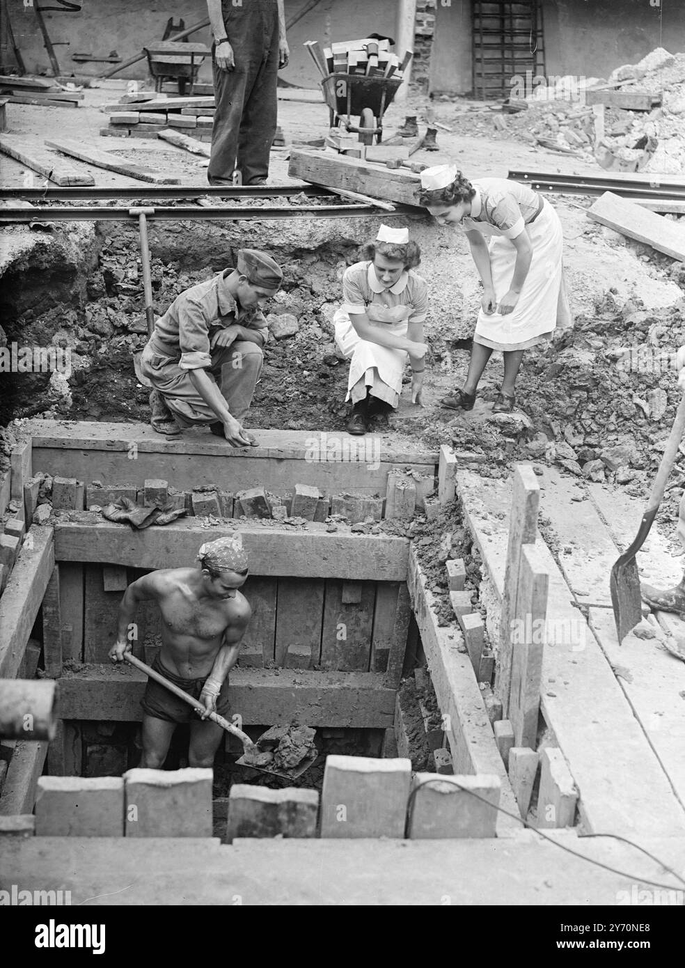 I PAZIENTI LASCIANO L'OSPEDALE SOTTO LA MINACCIA DI UNA BOMBA l'evacuazione di 345 pazienti è in corso presso l'University College Hospital di Londra a causa di una bomba inesplosa di 500 libbre, che si ritiene sia stata sganciata in un raid aereo tedesco nel 1941, è stata trovata vicino all'ospedale e si sta cercando di rimuoverlo. Anche la maggior parte dei 800 membri del personale residente sta lasciando l'edificio. La bomba si trova in un buco profondo nei siti di Grafton Street, al largo di Tottenham Court Road, dove le stanze dei negozi di mobili Maples sono state distrutte durante i raid aerei del 1941. L'IMMAGINE MOSTRA:-infermiera Pat Higgs (a sinistra) di Kingston- sul- Tamigi Foto Stock