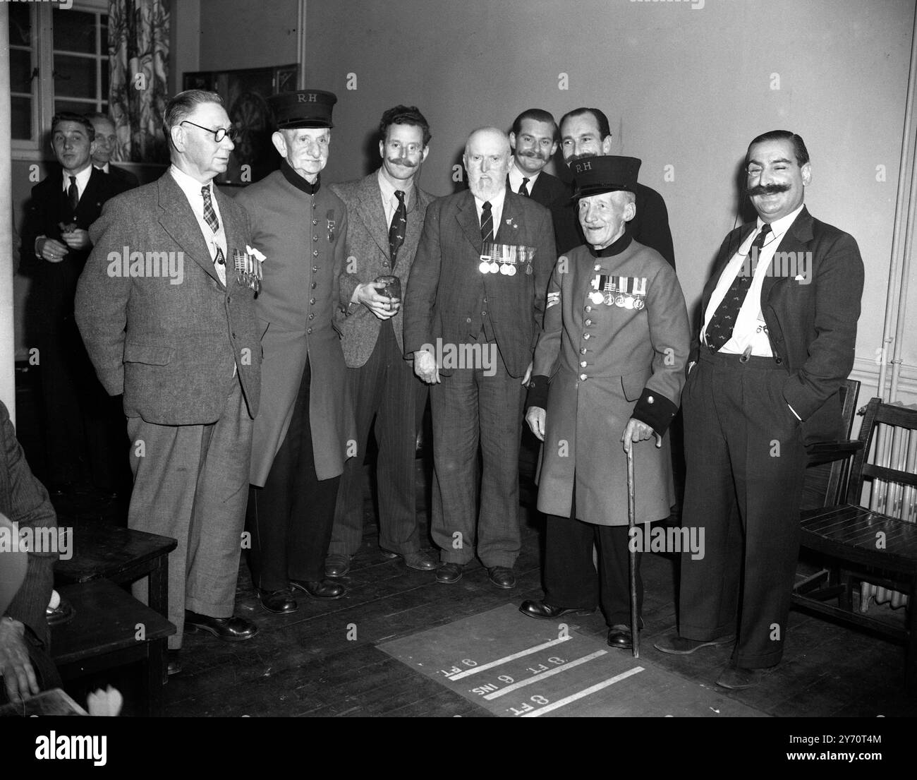 I membri del Handlebars Club , compreso Raymond Glendening , il loro presidente , hanno visitato il Victory Club (ex servizi) , in Seymour Street , Marble Arch , Londra , per una partita di freccette contro la squadra del club . Un dardo da quattro piedi fu reso disponibile per la partita. - Foto: Chelsea pensionati, STG Simmons , Late of the Rifles Brigade , 77 anni e Pte J H Davey 83 anni , Edward Hooker , Hearne Hill , con i suoi baffi al manubrio da 1/3 pollici , Raymond Glendening e altri . - 18 luglio 1949 Foto Stock