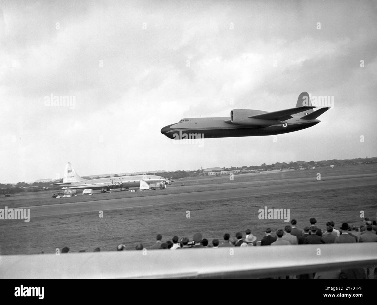 Con il Bristol Brabazon sullo sfondo , un bombardiere Short Brothers SA4 a lungo raggio vola sopra la testa dei visitatori alla mostra di volo e alla mostra dei costruttori di aerei britannici a Farnborough , Hampshire , Inghilterra . Il S.A.4 è alimentato da quattro motori Rolls-Royce Avon turbojet , montati in coppia . 11 settembre 1951 Foto Stock