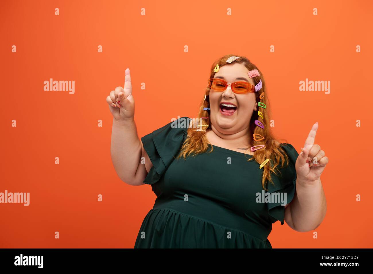 Una donna allegra e di grandi dimensioni con clip colorate si esprime su uno sfondo vivace. Foto Stock