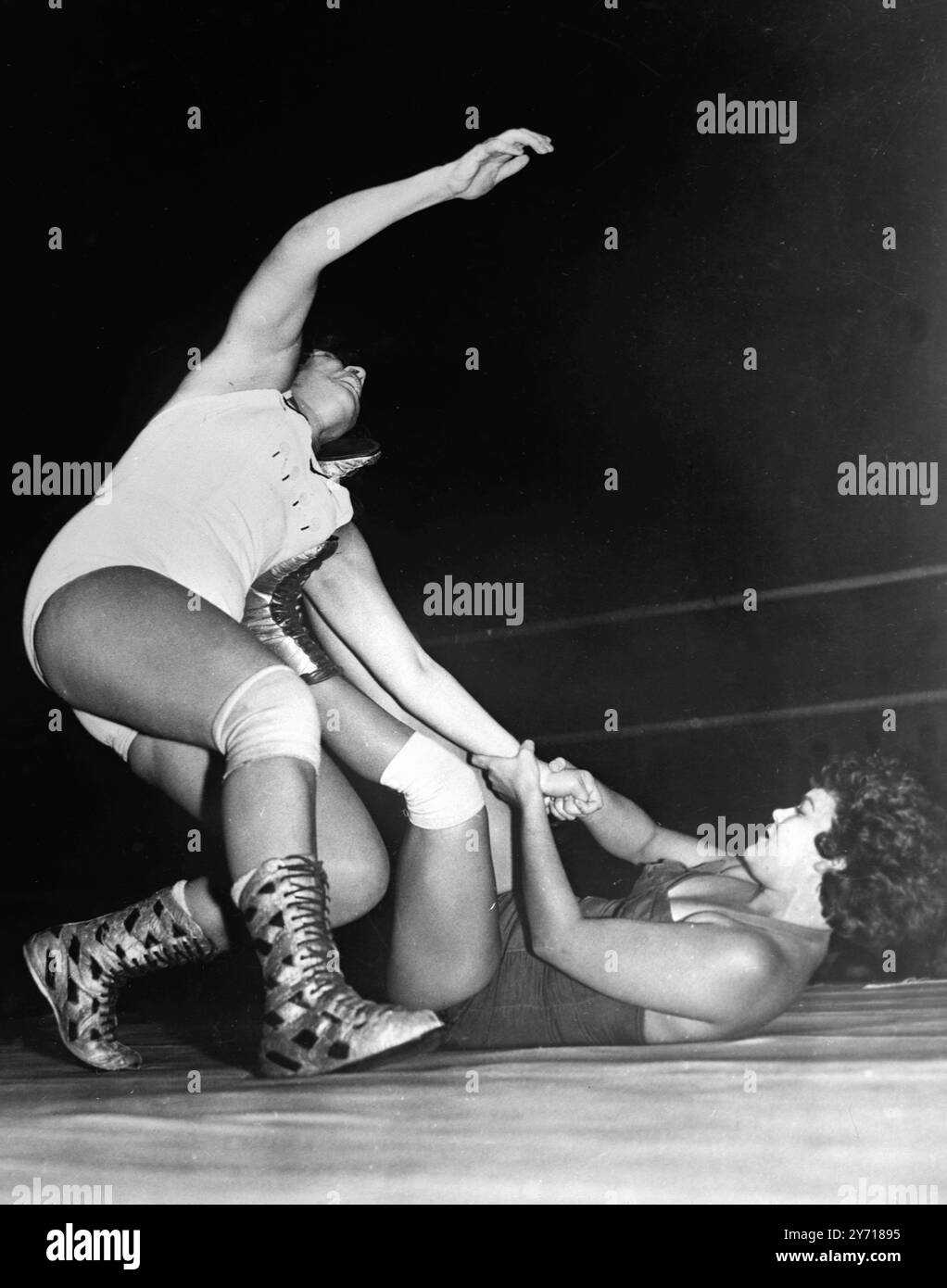 Un venditore continua casualmente a vendere il suo gelato mentre la lottatrice Betty Larkin viene abbattuta da Jerry Ford durante una gara di casa a Miami , Florida , USA . 22 settembre 1954 Foto Stock