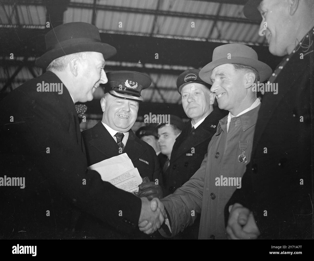GLI EROI FERROVIARI AL MOTORE CHE NOMINAVANO tra i 20 e i 30 di quel galante gruppo di lavoratori che eseguivano azioni valorose per mantenere aperte le linee durante la guerra formarono una Guardia d' onore alla stazione di Waterloo, Londra, quando Sir Eustace Missenden, presidente della British Railways, nominò una locomotiva di classe " Battaglia d' Inghilterra " come se stesso. SPETTACOLI DI IMMAGINI ;- I MEDAGLIATI GEORGE INCONTRANO SIR EUSTACE MISSENDEN . A destra stringendo la mano a Sir Eustace Missenden c'è il signor . GEORGE LEACH , Permanent Way man di Aldershot . La seconda a sinistra è HENRY SAVAGE , maestro di falciatura a Guildford . Entrambi hanno vinto George Medals per Foto Stock