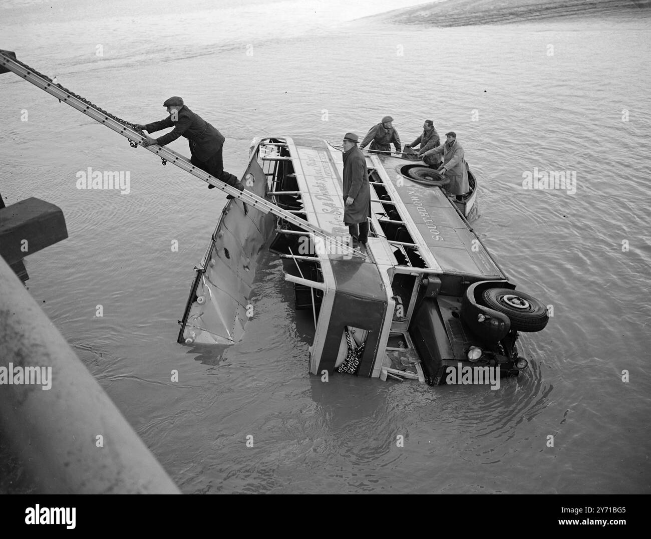 GALE SOFFIA IL BUS NEL FIUME ieri sera la gala ha fatto passare un autobus a due piani attraverso un ponte a Old Shoreham , Sussex , in un fiume a 20 piedi sotto , 25 persone sono rimaste intrappolate nel bus che viaggiava da Worthing a Brighton . Il fatto che la marea fosse bassa salvò i passeggeri dall'annegamento nel fiume Adur. Il tetto dell'autobus è stato strappato. I soccorritori si sono fatti strada attraverso la burrasca e sono scesi all'autobus con la scala, 14 passeggeri sono stati feriti e uno seriamente. I feriti sono stati portati in ospedale. L'IMMAGINE MOSTRA:- Una vista generale che mostra i lavoratori che si arrampicano sul bus mentre le catene vengono riparate Foto Stock