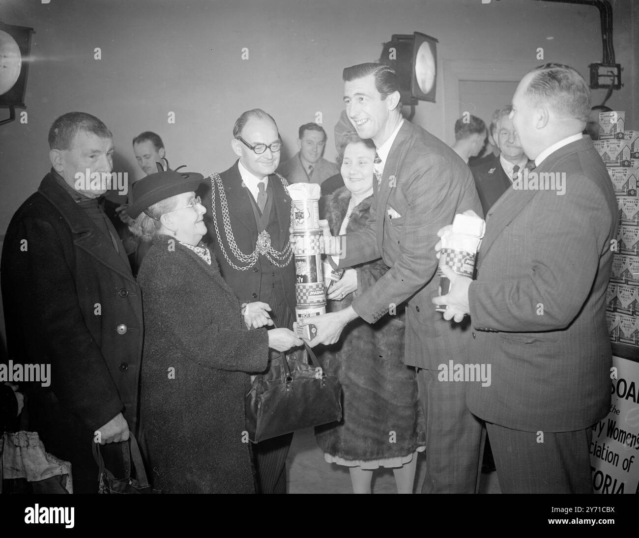 "" LANKY CHIPS " PRESENTA UN PACCO REGALO A 85 ANNI '' Lanky'' Chips - Rafferty , la star australiana del cinema che interpreta il ruolo di protagonista nel nuovo film australiano '' Eureka Stockade'' ( la première aprirà domani a Londra ) ha presentato pacchi regalo vittoriani contenenti cibo, grassi e sapone ai pensionati anziani al municipio di Lambeth ( Londra ) . LE IMMAGINI MOSTRANO:- Chips Rafferty consegna pacchi alla signora . Elizabeth Harsant, 85 anni. Sir Norman Martin ( Agente generale per Victoria ) è sulla destra , il sindaco di Lambeth ( consigliere Simpson ) e la Mayoress sono al centro . 2 Foto Stock