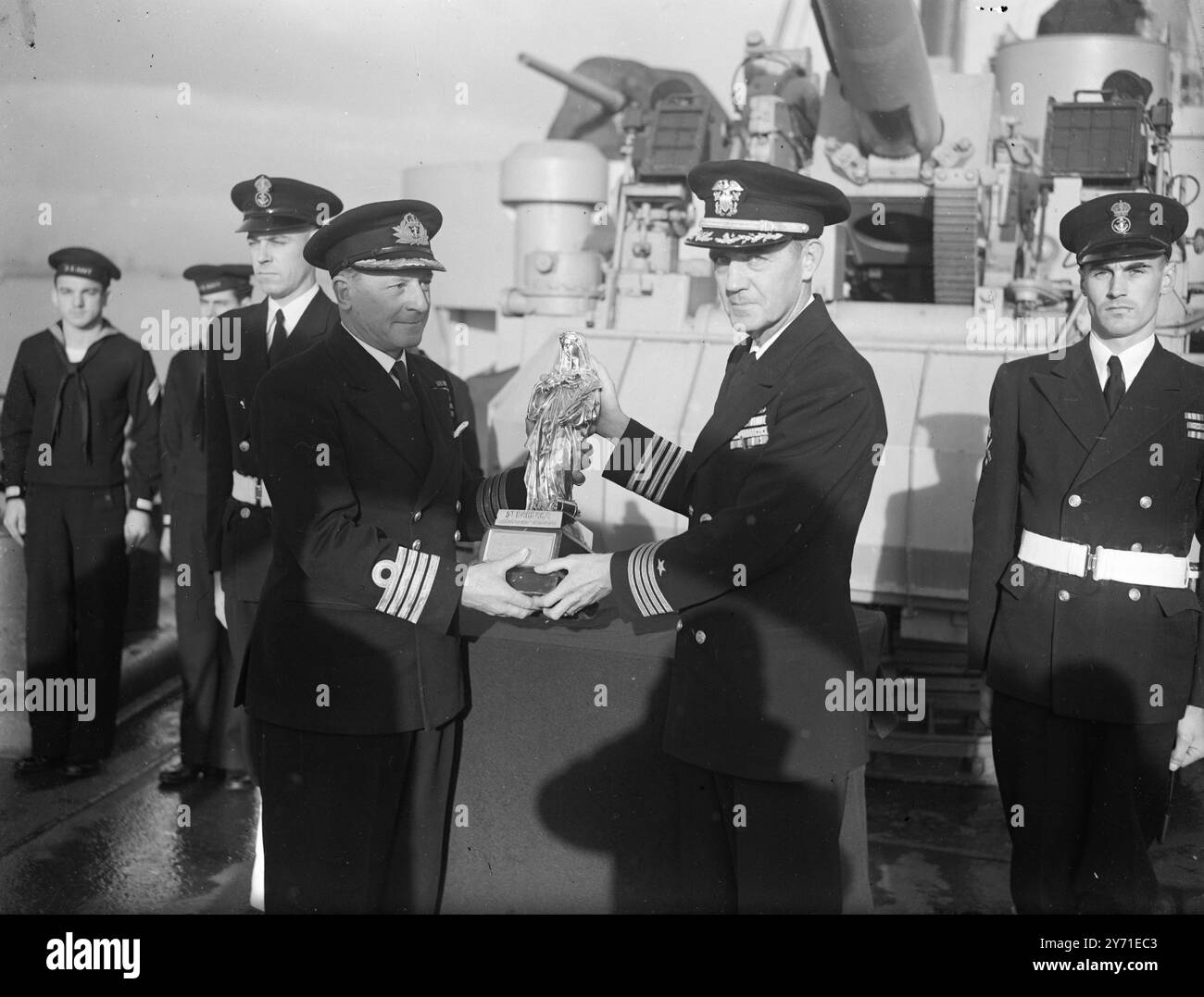 GUNNERY PATRON SAINT Dec 8th 1948 Captain McLaughlin, (a sinistra), consegna una replica argentata di St. Barbara al capitano W.S. PARSONS., United States Navy, a bordo della USS Mercury presso il porto di Portsmouth to-day (Mer). Sarà consegnato al sindaco di Santa Barbara, USA, come segno di relazioni amichevoli tra Santa Barbara e HMS Excellent, il Royal Naval Gunnery Establishment. Santa Barbara è stata adottata come santa patrona degli artisti l'8 dicembre 1948 Foto Stock