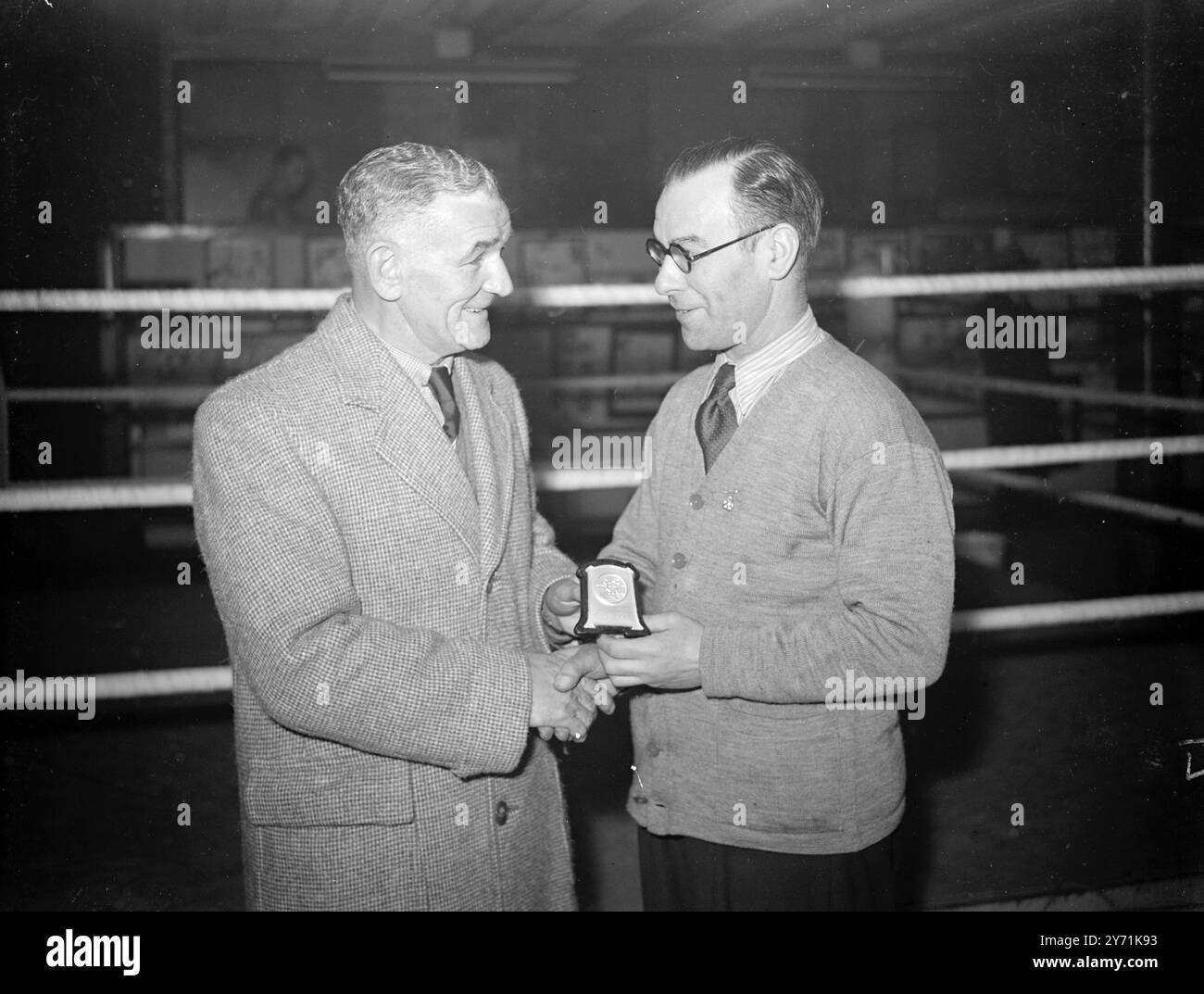 PRESENTAZIONE ALL'UOMO CHE HA ADDESTRATO FREDDIE MILLS ALLA FAMA. I VENDITORI NAT, l'addestratore di FREDDIE MILLS, ricevono una targa d'argento da TED BROADRIBB, manager di FREDDIE MILLS, in riconoscimento dei suoi sforzi per assistere Freddie sulla strada della fama, culminati nella vittoria del Campionato del mondo dei pesi leggeri. NAT ha formato 15 campioni britannici , europei , dell' Impero e del mondo . L'IMMAGINE MOSTRA;- TED BROADRIBB ( a sinistra 0 che presenta la targa d'argento ai VENDITORI NAT in una palestra di Londra. 27 novembre 1948 Foto Stock