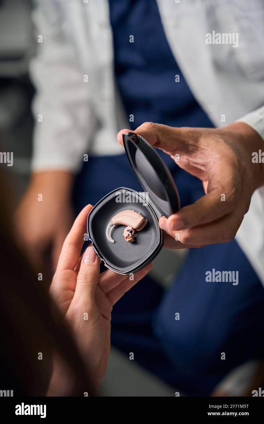Medico caucasico con custodia per apparecchio acustico per paziente Foto Stock